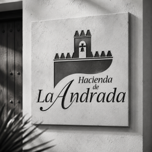 Branding para la Hacienda de la Andrada aplicado sobre una placa de aspecto pétreo en un muro de estilo tradicional.
