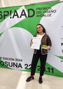 María Benítez Flores, premiada por un proyecto de su formación en diseño gráfico, muestra su diploma y galardón AAD 2024.
